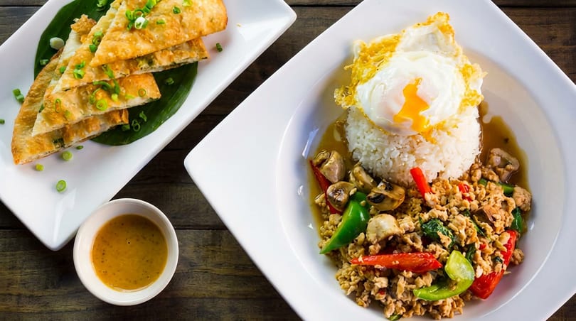Two Thai dishes: chicken basil with fried egg and rice, and scallion pancakes with dipping sauce.