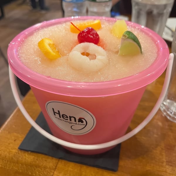 Heng restaurant's pink bucket of frozen drink, garnished with lychee, cherry, orange, lime, and pineapple.
