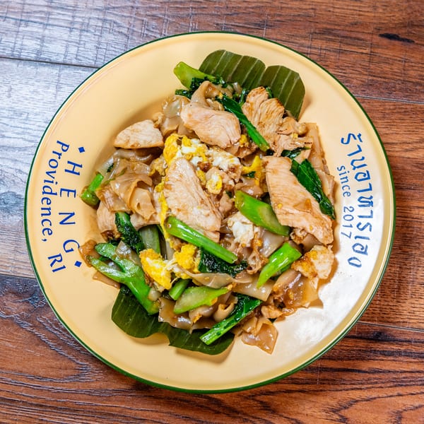 Pad See Ew with chicken, egg, and Chinese broccoli on a yellow Heng Providence plate.