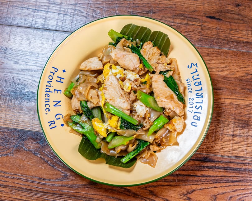 Pad See Ew with chicken, egg, and Chinese broccoli on a yellow Heng Providence plate.