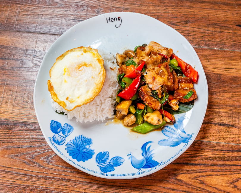 Crispy pork belly stir-fry with rice and a fried egg on a decorative plate.